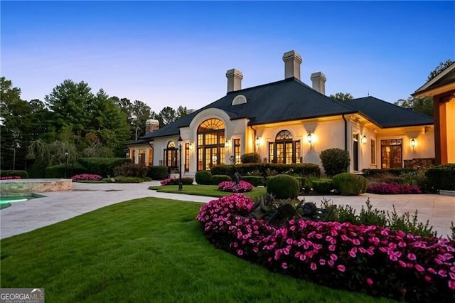 back house at dusk with a lawn