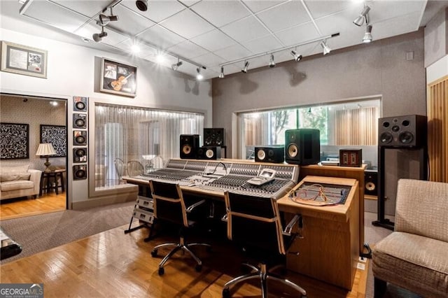 home office featuring a towering ceiling, wood-type flooring, and track lighting