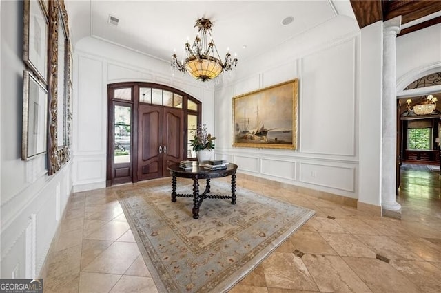 entrance foyer with an inviting chandelier and ornate columns