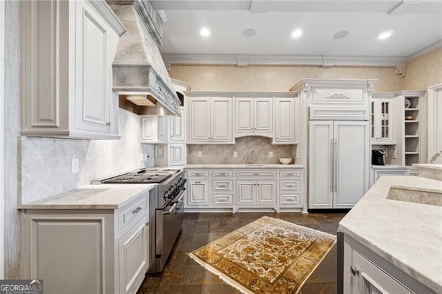 kitchen featuring white cabinets, high end appliances, sink, custom exhaust hood, and ornamental molding