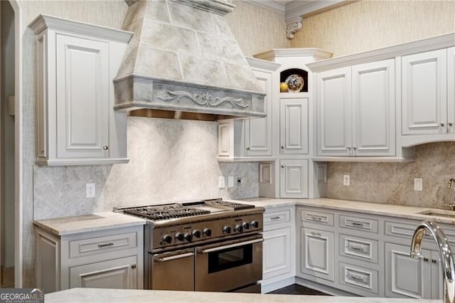 kitchen featuring tasteful backsplash, custom range hood, sink, double oven range, and white cabinetry