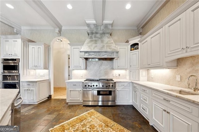 kitchen with beam ceiling, sink, stainless steel appliances, and white cabinets