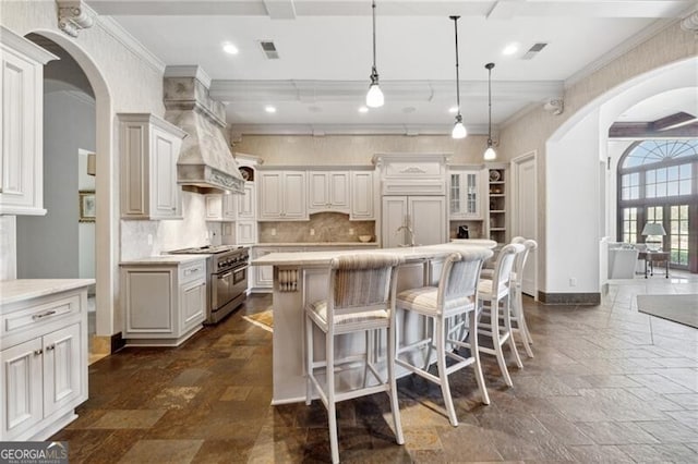 kitchen with decorative light fixtures, premium appliances, a breakfast bar area, and a kitchen island with sink