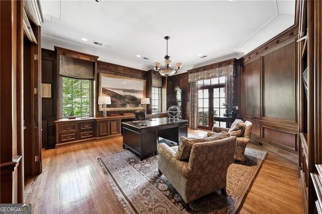 office featuring wood walls, an inviting chandelier, and light wood-type flooring