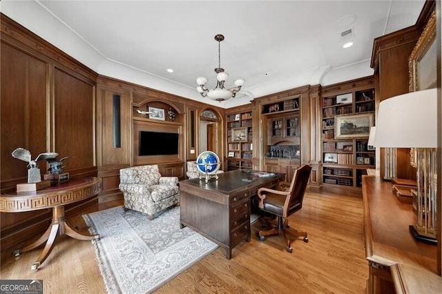 home office featuring light hardwood / wood-style flooring, ornamental molding, built in shelves, and a notable chandelier