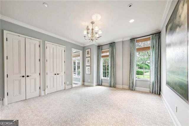 interior space with a notable chandelier, crown molding, multiple closets, and light carpet