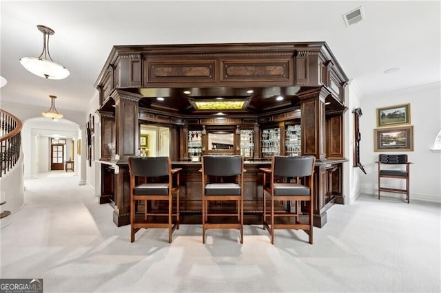 bar with light carpet, dark brown cabinetry, and decorative light fixtures