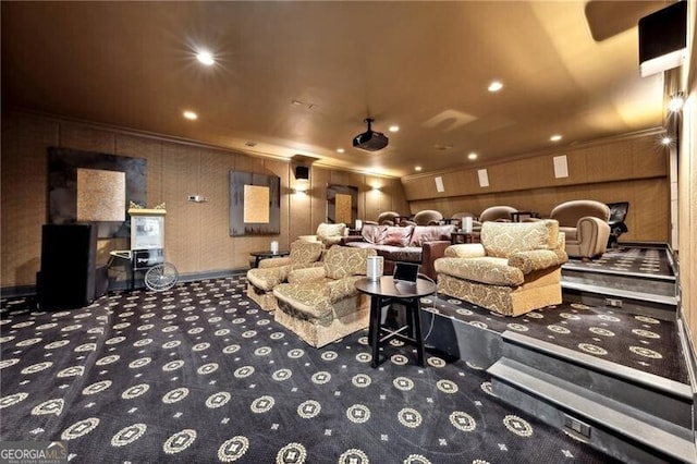 cinema room with ornamental molding, carpet flooring, and wooden walls