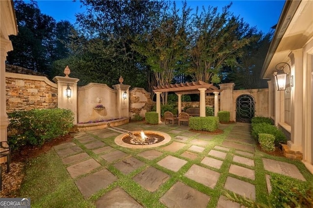 patio terrace at dusk with a fire pit and a pergola