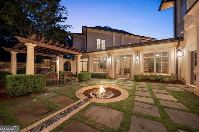 back house at dusk with an outdoor fire pit, a patio area, and a pergola