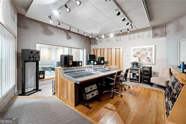 office area with track lighting, a towering ceiling, and light hardwood / wood-style floors