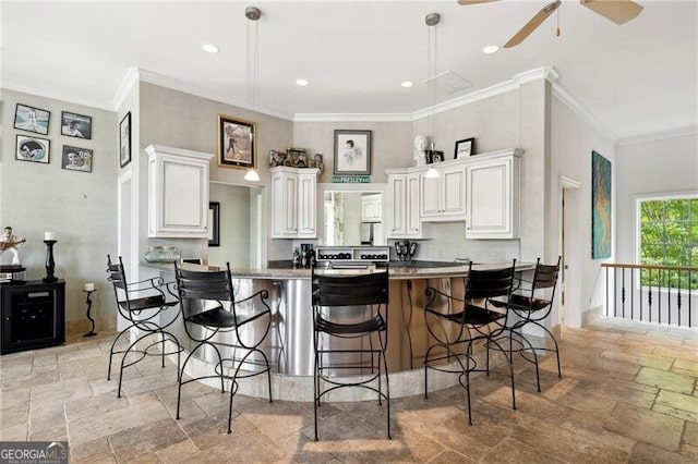 kitchen with white cabinets, ornamental molding, a kitchen breakfast bar, and kitchen peninsula