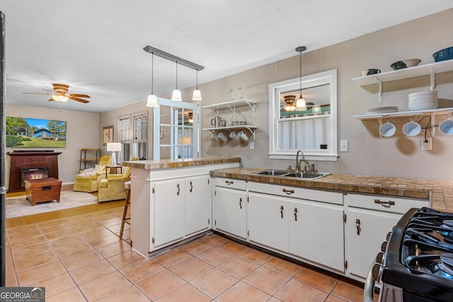 kitchen featuring hanging light fixtures, sink, kitchen peninsula, and white cabinetry