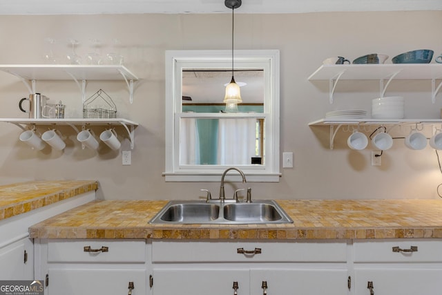 kitchen featuring pendant lighting, sink, and white cabinetry