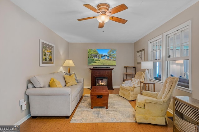 living room featuring ceiling fan, heating unit, and light hardwood / wood-style flooring