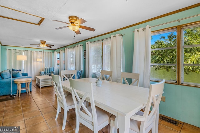 tiled dining room with ceiling fan, crown molding, and a water view