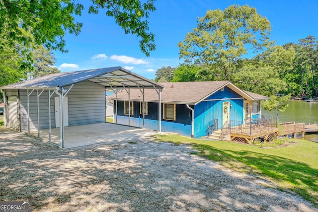 back of house featuring a yard, an outbuilding, a carport, and a water view