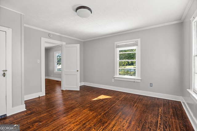 empty room with dark hardwood / wood-style floors, ornamental molding, and a healthy amount of sunlight