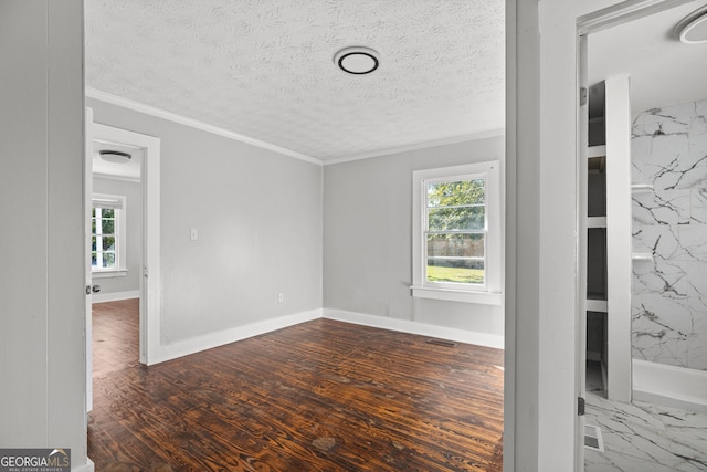 empty room featuring ornamental molding, dark wood-type flooring, tile walls, and a textured ceiling