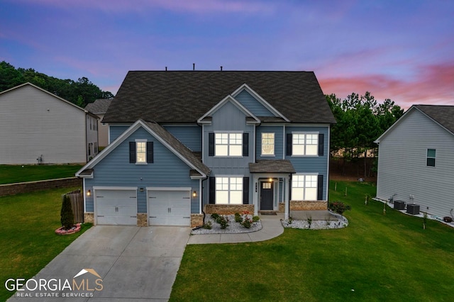 view of front of house with a garage, a lawn, and central AC