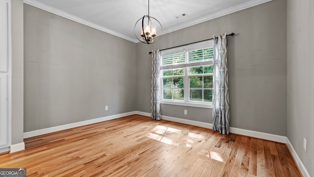 empty room featuring crown molding, a chandelier, and light wood-type flooring