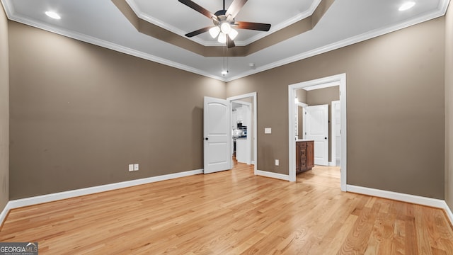 unfurnished bedroom with ceiling fan, ornamental molding, a raised ceiling, and light wood-type flooring