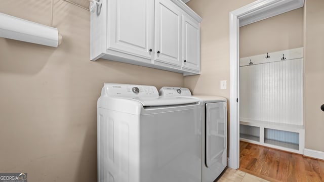 clothes washing area with separate washer and dryer, light hardwood / wood-style floors, and cabinets