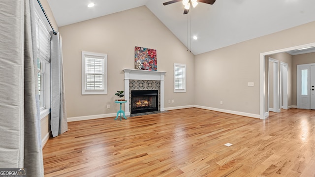 unfurnished living room with ceiling fan, high vaulted ceiling, a fireplace, and light hardwood / wood-style floors