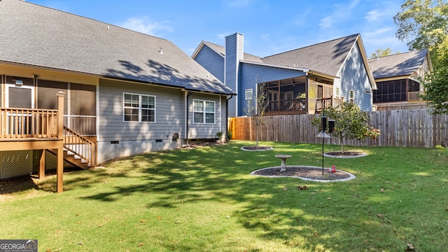 rear view of property featuring a wooden deck, a yard, and a sunroom