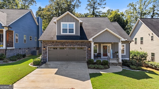 craftsman house featuring a porch, a garage, central AC unit, and a front yard