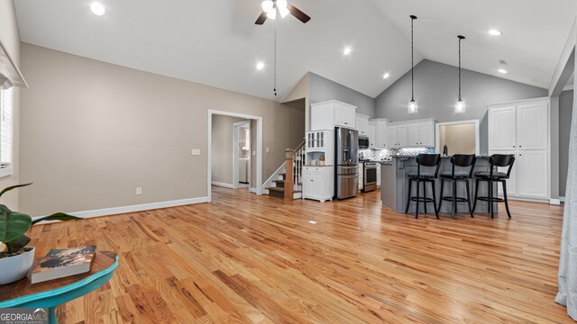 living room featuring ceiling fan, high vaulted ceiling, and light wood-type flooring