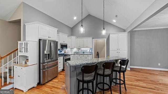 kitchen featuring light hardwood / wood-style flooring, hanging light fixtures, stainless steel appliances, white cabinets, and a kitchen island