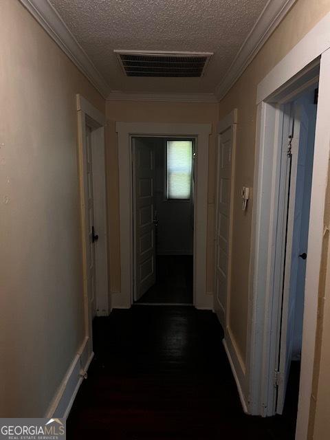 hallway with crown molding and a textured ceiling