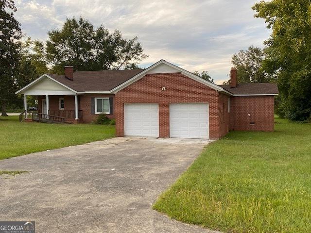 ranch-style home featuring a garage, a front yard, and covered porch