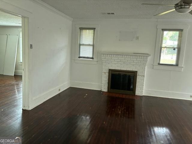 unfurnished living room featuring ceiling fan, dark hardwood / wood-style flooring, a brick fireplace, and a textured ceiling