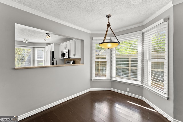 unfurnished dining area featuring a textured ceiling, crown molding, and dark hardwood / wood-style floors