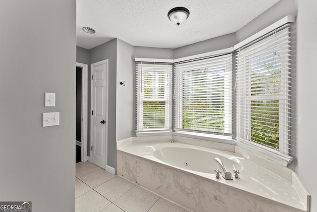 bathroom with tile patterned floors, a tub to relax in, a textured ceiling, and a wealth of natural light