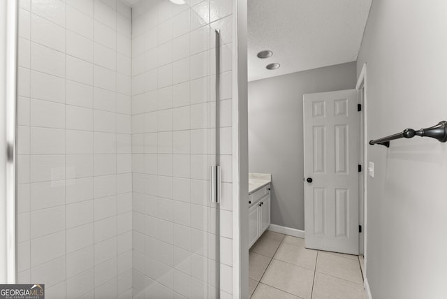 bathroom with tile patterned flooring, vanity, a shower with door, and a textured ceiling