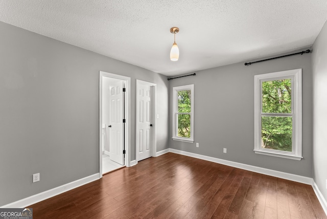 unfurnished bedroom with dark hardwood / wood-style floors and a textured ceiling