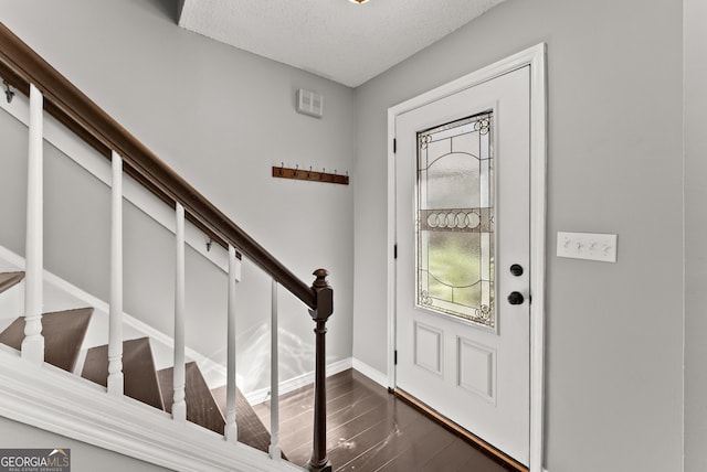 foyer entrance with dark hardwood / wood-style flooring and a textured ceiling