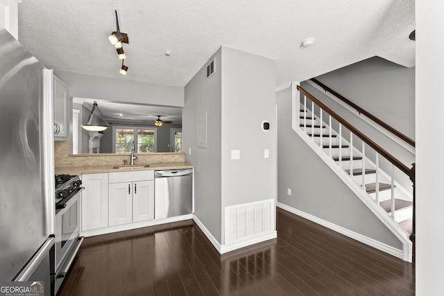 kitchen featuring pendant lighting, stainless steel appliances, white cabinetry, and dark wood-type flooring