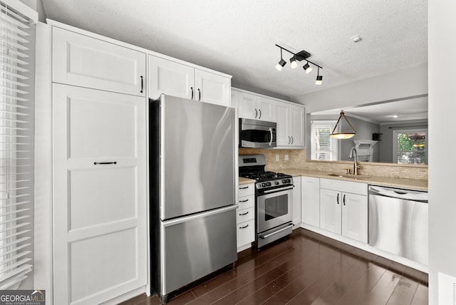 kitchen with appliances with stainless steel finishes, dark hardwood / wood-style floors, white cabinetry, and sink