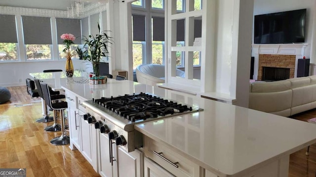 kitchen with a breakfast bar, stainless steel gas stovetop, light hardwood / wood-style floors, and plenty of natural light