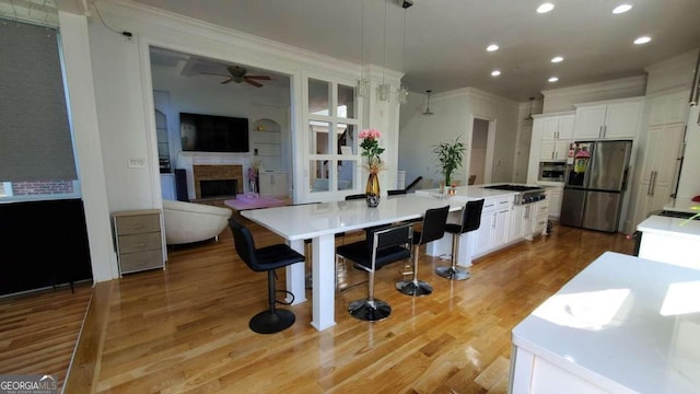 kitchen featuring appliances with stainless steel finishes, white cabinets, decorative light fixtures, and a large island