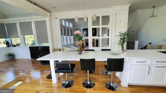 kitchen with white cabinetry, a healthy amount of sunlight, decorative light fixtures, and light wood-type flooring