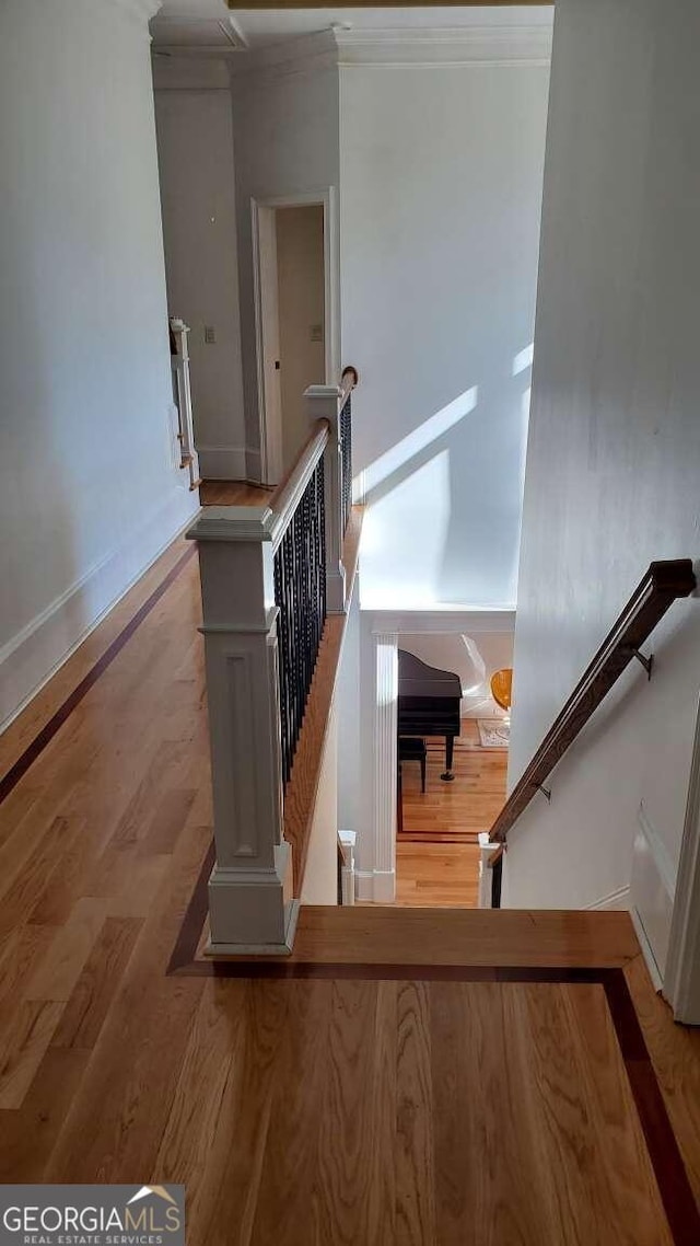 staircase with ornamental molding and hardwood / wood-style floors