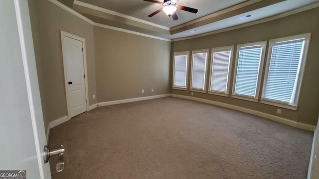 empty room with ornamental molding, a tray ceiling, carpet, and ceiling fan