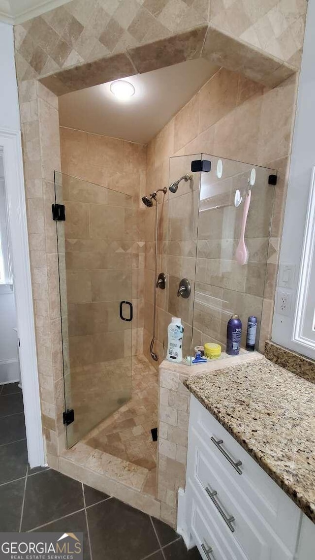 bathroom featuring a shower with door, vanity, and tile patterned flooring