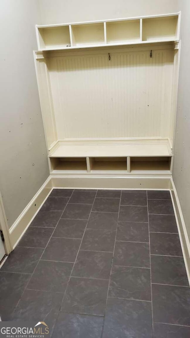 mudroom with dark tile patterned floors