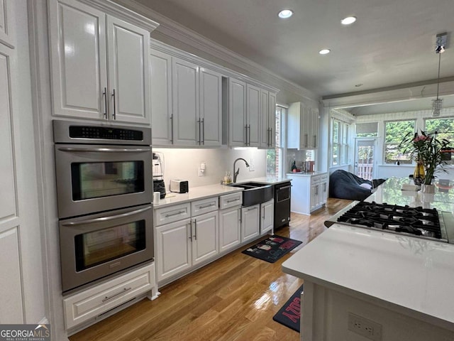 kitchen featuring recessed lighting, light countertops, a sink, light wood-style flooring, and stainless steel appliances